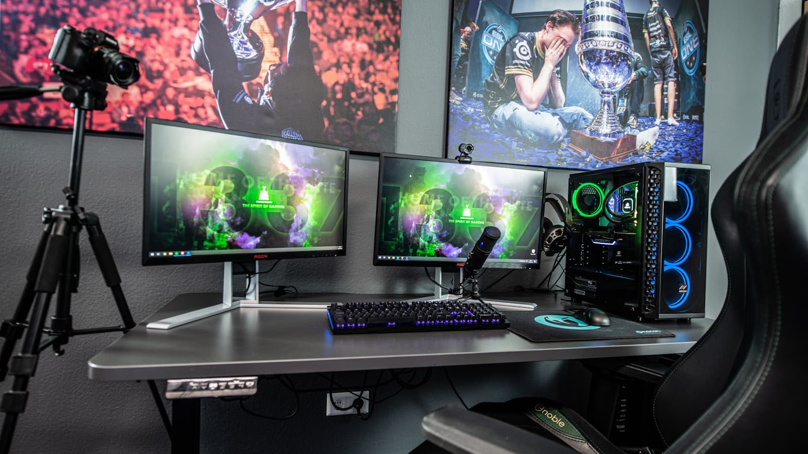 Creator's desk with several monitors, a camera on a tripod and studio lighting set up for filming